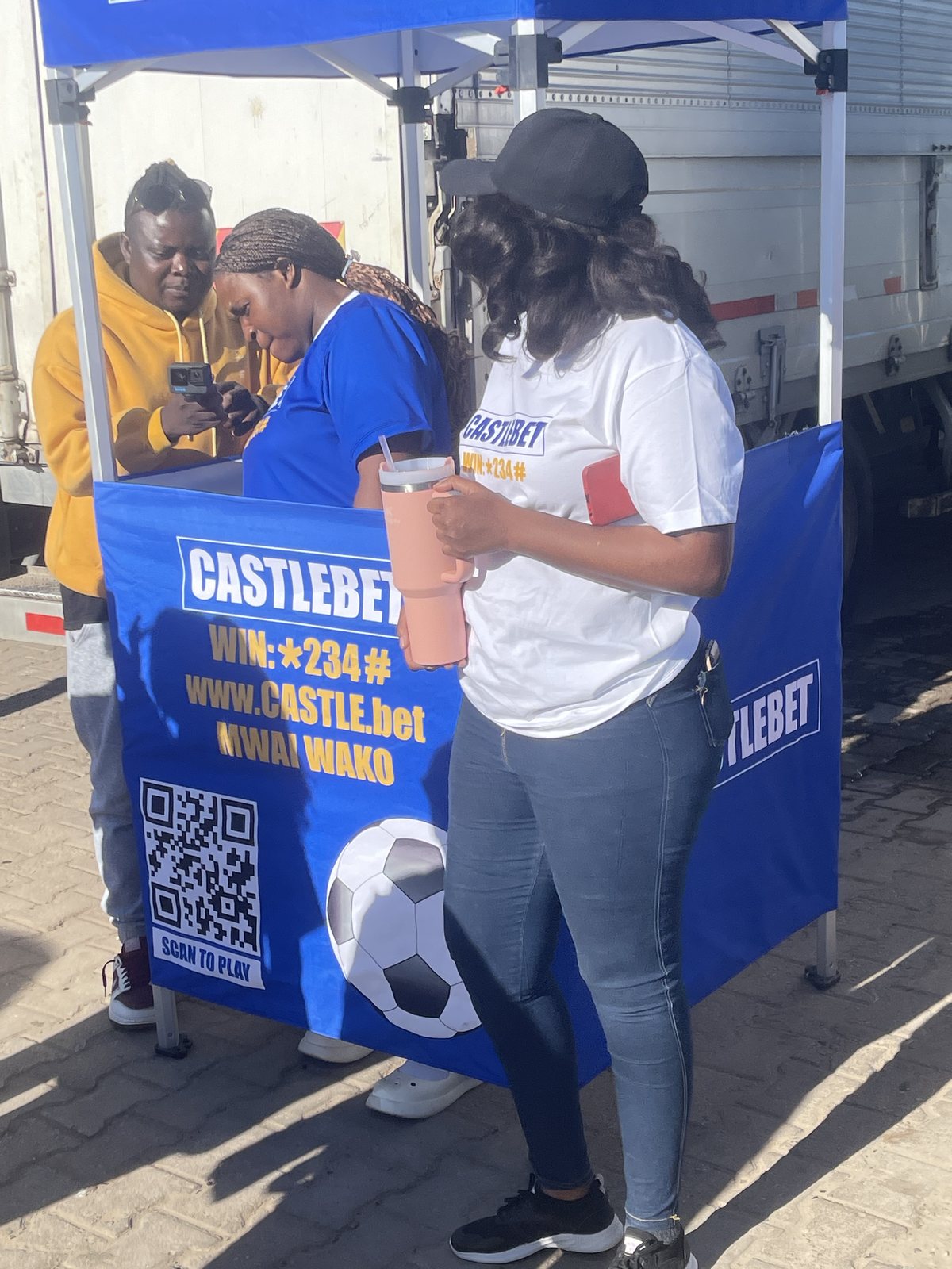 CastleBet promoters supporting an attendee at a branded engagement booth